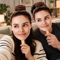 Couple on a sofa holding personalized big head face cutouts on wooden sticks